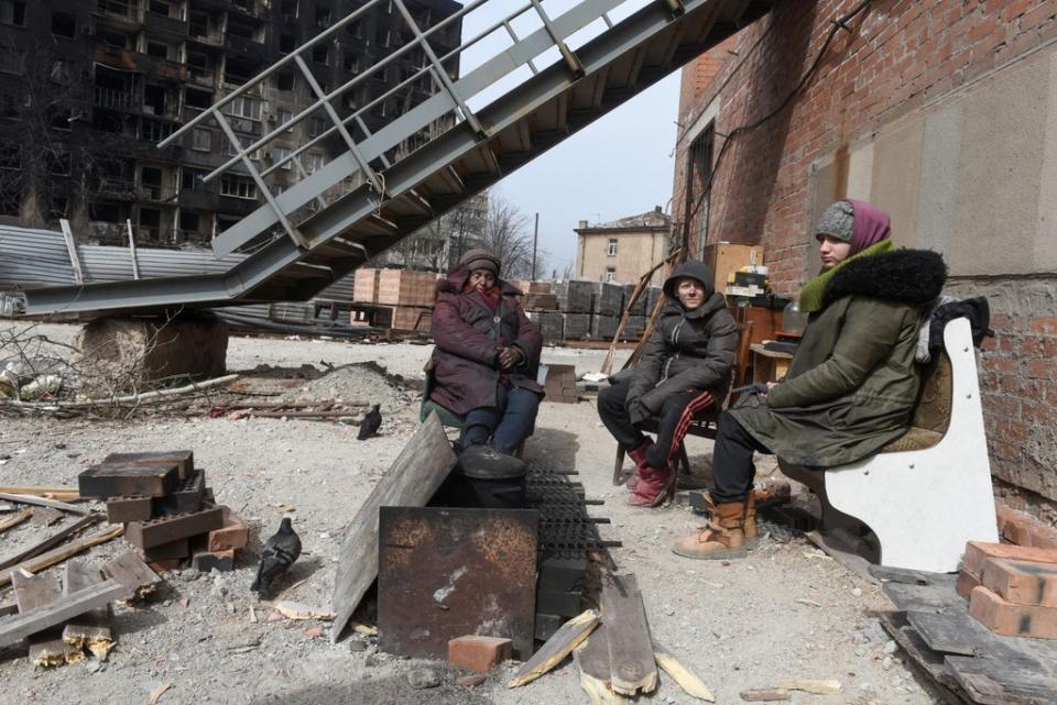 Marina Sidorenko, 83, and other local residents sit around a fire on territory of a church in Mariupol (REUTERS)