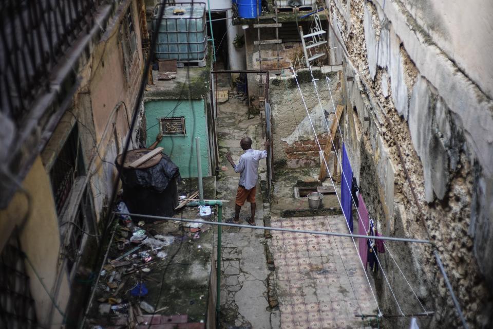 Mario Luis Poll habla con un vecino dentro de una desvencijada mansión en la que viven seis familias en la calle Villegas en La Habana, Cuba, el jueves 5 de octubre de 2023. El restaurador de arte de 57 años, que ha vivido durante 19 años en el inmueble, ha hecho reparaciones para tratar de mantener firme el techo de su estancia, después de que el piso del nivel superior colapsara. (AP Foto/Ramón Espinosa)