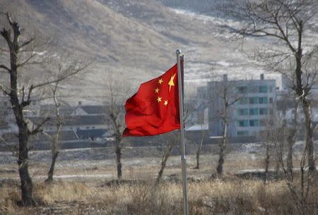 China's national flag flutters on the Chinese side of the banks of the Tumen river, as a North Korean village is seen behind, in Tumen, China, January 7, 2016. REUTERS/Kim Kyung-Hoon