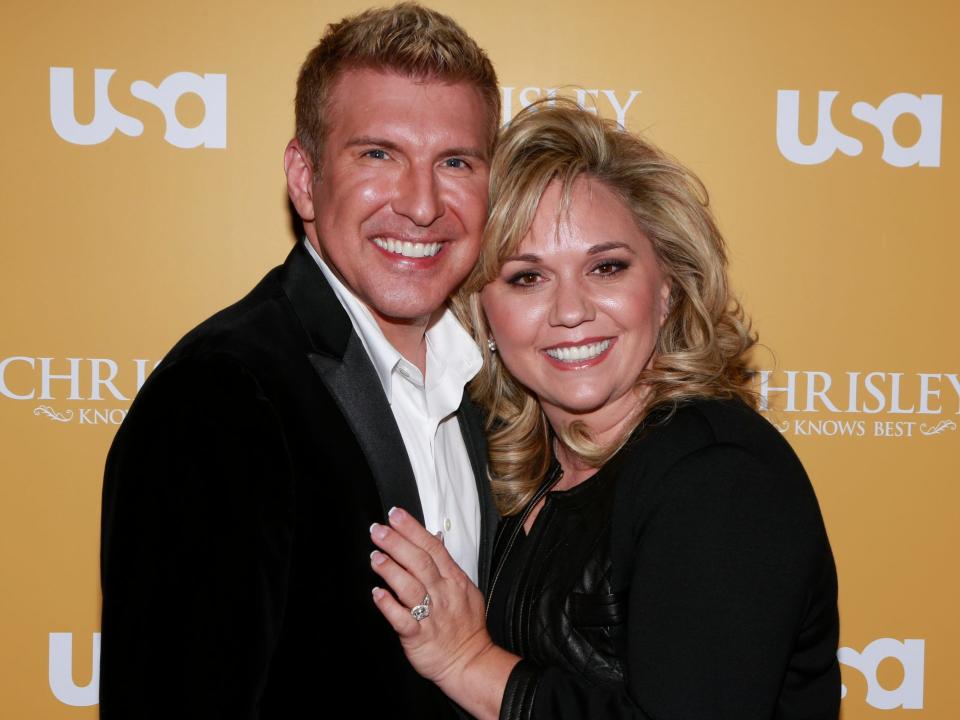 todd chrisley and julie chrisley in front of a yellow USA today sign with her hand on his chest