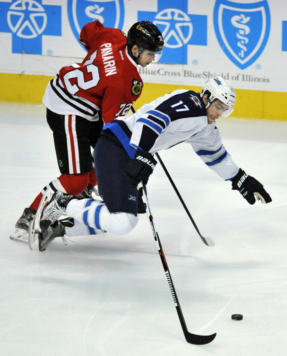 Winnipeg Jets' Adam Lowry (17) battles Chicago Blackhawks' Artemi Panarin (72) of Russia, for a loose puck during the first period of an NHL hockey game Tuesday, Dec. 27, 2016, in Chicago. Winnipeg won 3-1. (AP Photo/Paul Beaty)