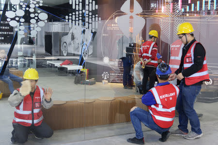 Workers set up the display stand for Chinese EV startup Singulato Motors in preparation for the upcoming auto show in Shanghai, China April 14, 2019. Picture taken April 14, 2019. REUTERS/Norihiko Shirouzu
