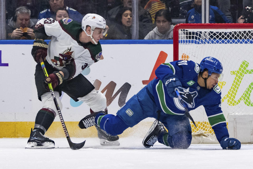 Arizona Coyotes' Travis Dermott (33) trips Vancouver Canucks' Dakota Joshua (81) during the second period of an NHL hockey game Thursday, Jan. 18, 2024, in Vancouver, British Columbia. (Ethan Cairns/The Canadian Press via AP)