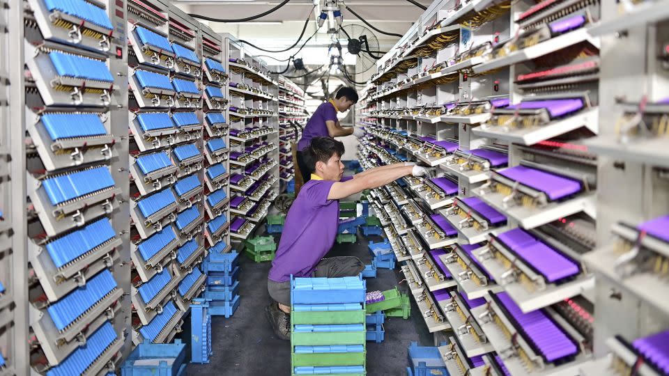 An employee tests cylindrical cells at a factory producing lithium-ion batteries, used in electric vehicles, in June 2024 in Fuzhou, China. - Zhu Haipeng/VCG/AP