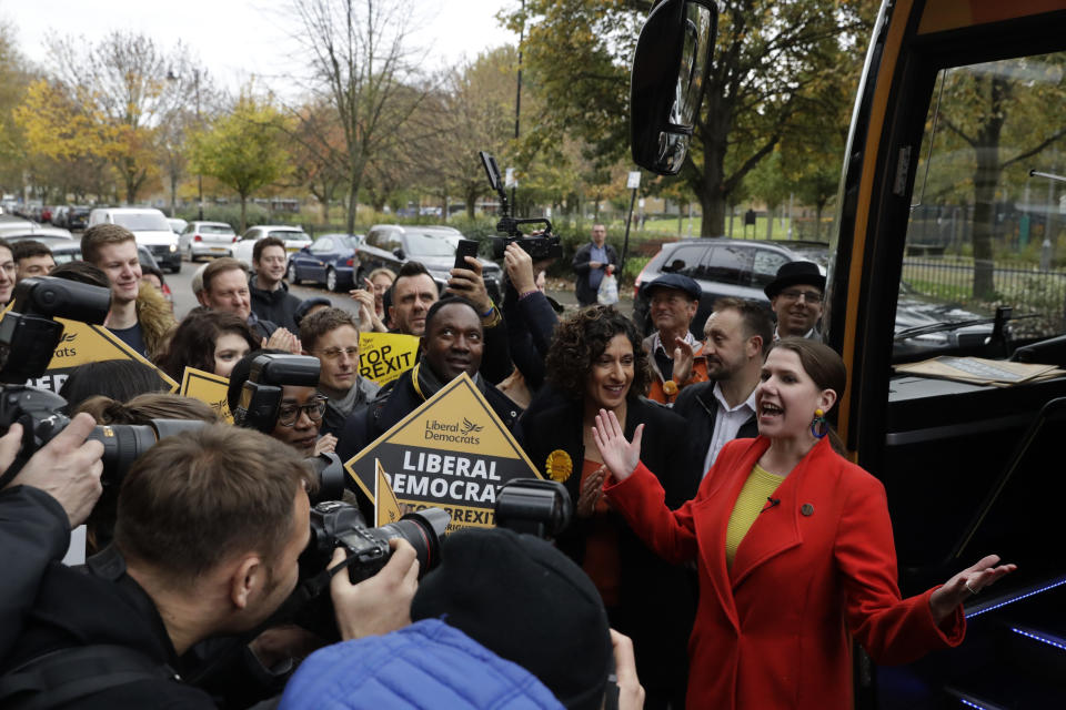 Britain's Liberal Democrats leader Jo Swinson reacts as she is greeted by supporters as she gets off her campaign bus and then stands flanked by Humaira Ali, third right, the Liberal Democrats candidate for Southwark and Old Bermondsey as she arrives to campaign at Cafe Amisha in the Southwark and Old Bermondsey constituency in south London, Saturday, Nov. 16, 2019. (AP Photo/Matt Dunham)