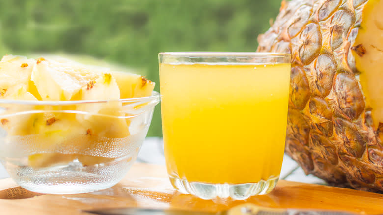 A glass of pineapple juice and pineapple slices 