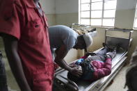 A relative closes the eyes of a protester allegedly shot by police at the Nairobi funeral home, Kenya Wednesday, June 26, 2024. Thousands of protesters stormed and burned a section of Kenya's parliament Tuesday to protest tax proposals. Police responded with gunfire and several protesters were killed. (AP Photo/Brian Inganga)