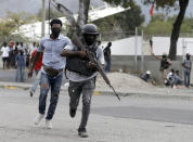 Off-duty police officers run towards and armed clash with army soldiers during a protest over police pay and working conditions, in Port-au-Prince, Haiti, Sunday, Feb. 23, 2020. Off-duty police officers and their supporters exchanged fire for nearly two hours with members of the newly reconstituted Haitian army in front of the national palace. (AP Photo/Dieu Nalio Chery)