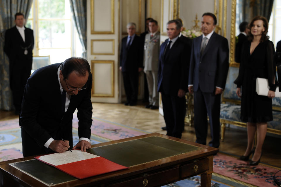 François Hollande reçoit l'insigne de Grand maître de l'Ordre de la Légion d'honneur avant de signer un registre avant de se rendre, entouré du président du Sénat et du président de l'Assemblée nationale, dans la salle des fêtes où l'attendent tous ses invités. AFP