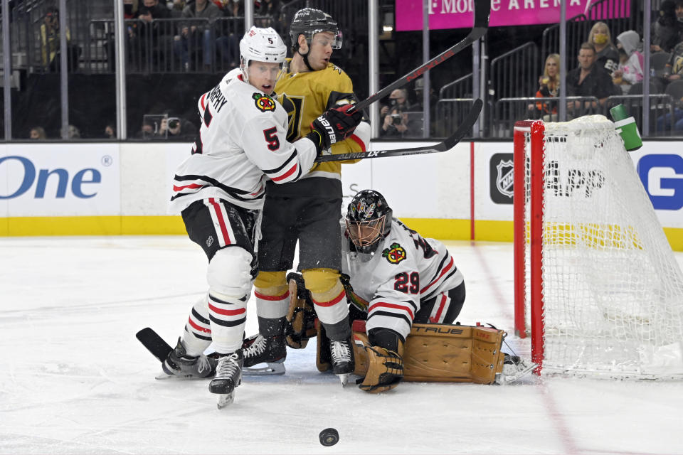 Vegas Golden Knights right wing Evgenii Dadonov (63) is caught between Chicago Blackhawks defenseman Connor Murphy (5) and goaltender Marc-Andre Fleury (29) during the second period of an NHL hockey game Saturday, Jan. 8, 2022, in Las Vegas. (AP Photo/David Becker)