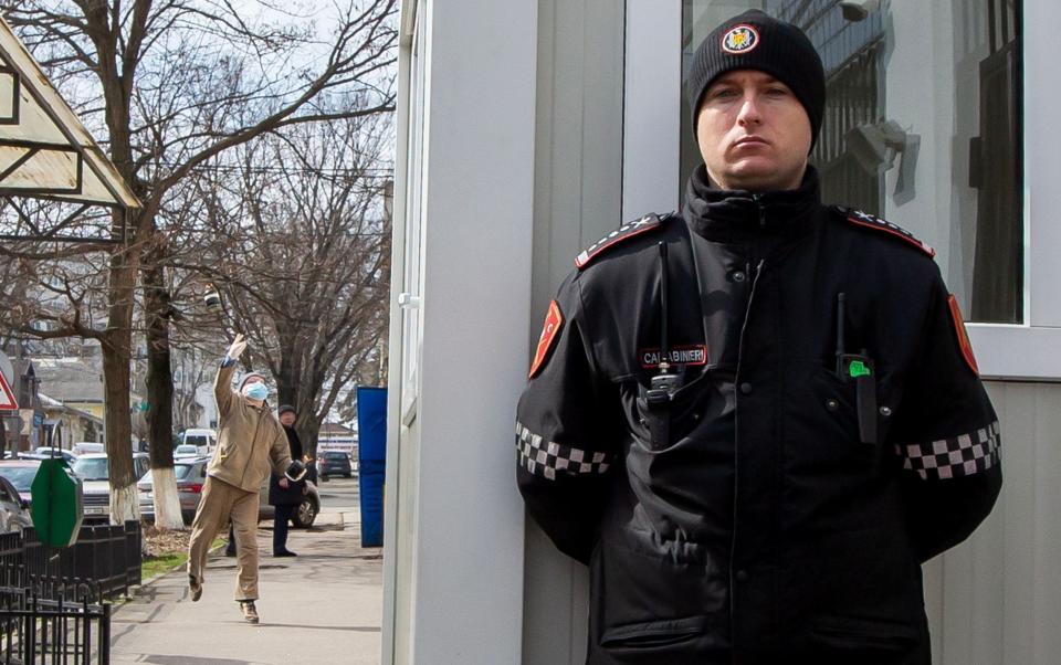 A Carabinieri officer (R) stands guard, unaware that a man (L) wearing a mask is throwing a handmade Molotov cocktail towards the Russian Embassy in Chisinau, Moldova