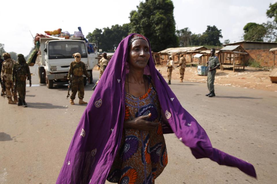 At PK12, the last checkpoint at the exit of the town, a Muslim woman who was on a truck attacked by looters walks to join another vehicle, as Chadian soldiers protect the lorry as thousands of Muslim residents from Bangui and Mbaiki flee the Central African Republic capital Bangui in a mass exodus using cars, pickups, trucks, lorries and motorcycles, Friday, Feb. 7, 2014. Tit-for-tat violence killed more than 1,000 people in Bangui alone in a matter of days in December. An untold number have died in the weeks that followed, with most of the attacks in Bangui targeting Muslims. (AP Photo/Jerome Delay)