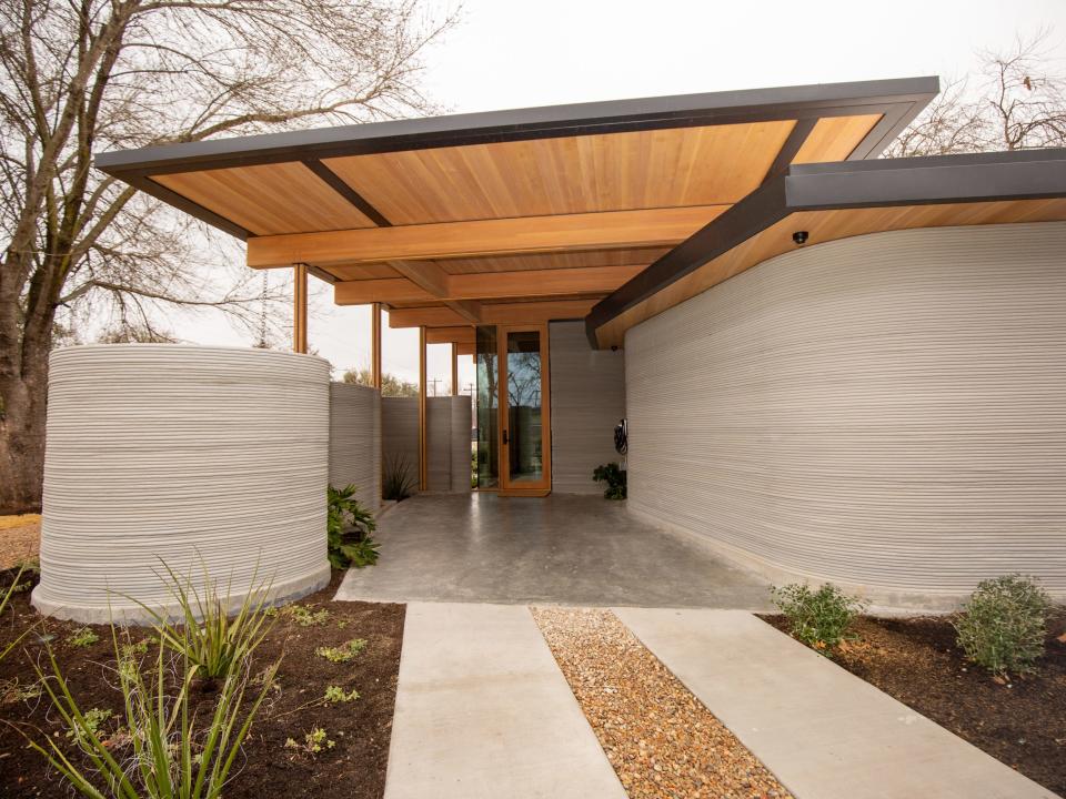 Icon's over 2,000-square-foot House Zero in Austin. The exterior of the home is made of layered printed concrete that hold up the wooden roof. The shaded area is the car park.