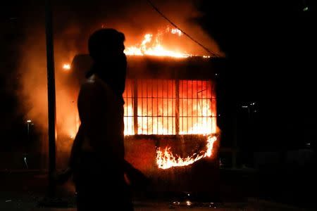 Un manifestante pasa frente a un quiosco en llamas durante una protesta contra el presidente Nicolás Maduro en Caracas. 10 de abril de 2017. Un joven murió por un disparo en Venezuela durante una manifestación contra el gobierno de Nicolás Maduro la noche del lunes, informó la Fiscalía en un comunicado, elevando a dos el número de fallecidos tras una nueva ola de protestas callejeras en la nación sudamericana. REUTERS/Carlos Garcia Rawlins