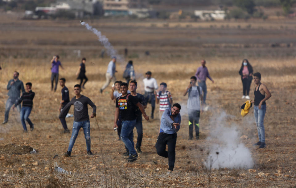 Palestinian student throws back teargas fired by Israeli near a school in the village of Sawyeh near the West Bank city of Nablus, Monday, Oct. 15, 2018. The Israeli military closed down the 500 student school in Sawyeh yesterday following stone throwing protests, but the students defied the decision and came with their families to the schools Monday, (AP Photo/Majdi Mohammed)