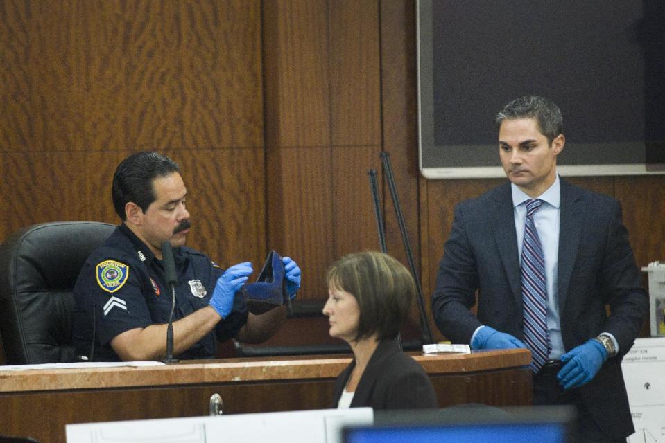 Houston police officer Ernest Aguilera, left, examines a stiletto shoe entered into evidence by prosecutor John Jordan, right, during the trial against Ana Lilia Trujillo Tuesday, April 1, 2014, in Houston. Trujillo, 45, is charged with murder, accused of killing her 59-year-old boyfriend, Alf Stefan Andersson with the heel of a stiletto shoe, at his Museum District high-rise condominium in June 2013. (AP Photo/Houston Chronicle, Brett Coomer) MANDATORY CREDIT