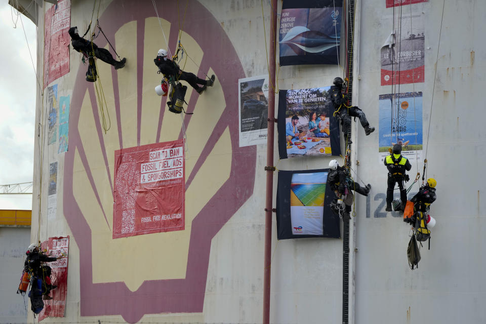 FILE- In this Monday, Oct. 4, 2021, file photo, Dutch police, second right and fourth right, top, break up a demonstration of Greenpeace climate activists who lowered themselves from a fuel storage tank during a protest at a Shell refinery in Rotterdam, Netherlands. The Netherlands' biggest pension fund announced Tuesday Oct. 26, 2021, that it will stop investing in companies that produce fossil fuels, saying the move that has long been demanded by members of the fund was prompted by recent climate reports by the United Nations and International Energy Agency. (AP Photo/Peter Dejong, file)