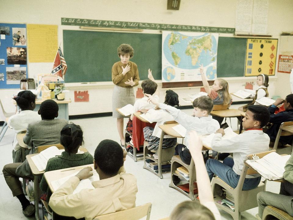 A teacher speaks at the front of a classroom in 1969