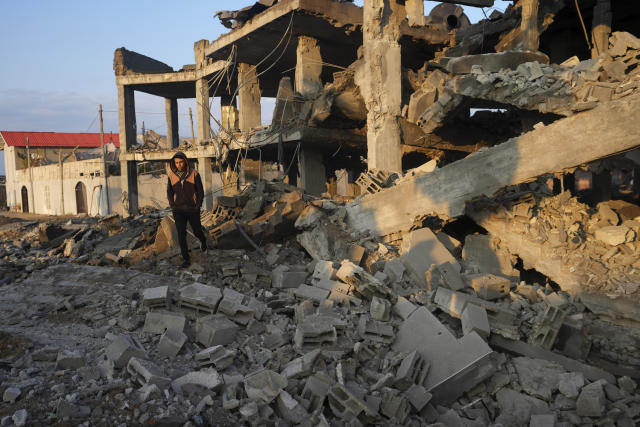 A young man walks through the rubble of a destroyed building hit by Israeli airstrikes in Gaza City, Monday, Feb. 13, 2023. Earlier on Monday, the Israeli military said aircraft bombed a Hamas rocket manufacturing site and military installations in the Gaza Strip after Palestinian militants launched four rockets into southern Israel overnight. (AP Photo/Adel Hana)