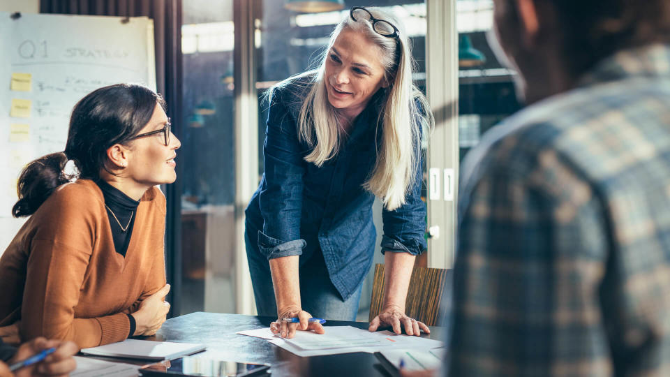 Senior business woman explaining business matters to her team in a boardroom.