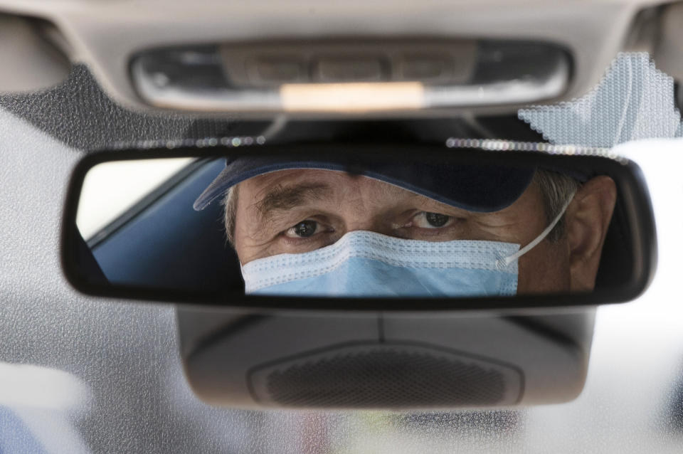 Taxi driver Nicolae Hent, wearing a protective mask, poses for a photograph before before starting work in New York, Monday, April 6, 2020. A taxi driver's job was already tougher in recent years with the arrival of ride-sharing companies such as Uber and Lyft. The empty streets during the coronavirus pandemic have made things more difficult. (AP Photo/Matt Rourke)