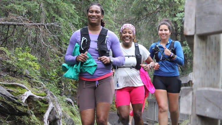 Three runners follow a trail in the forest