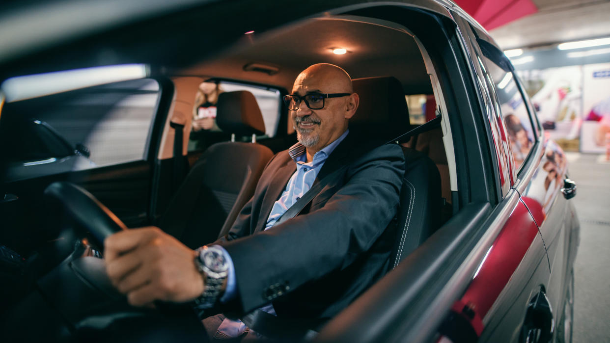 Smiling bearded senior adult driving car at night.