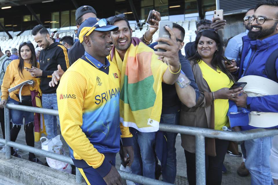 Sri Lanka's Angelo Mathews takes pictures with fans at the end of the Cricket World Cup match against England in Leeds, England, Friday, June 21, 2019. (AP Photo/Jon Super)