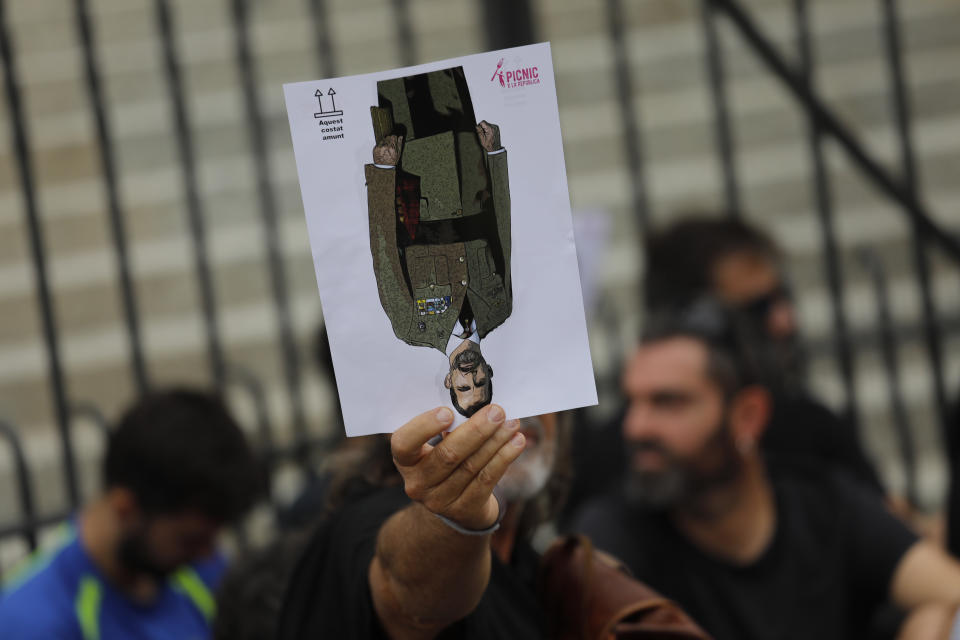 A protester holds a portrait of Spain's King Felipe upside down during a pro-independence gathering on the fifth day of protests over the conviction of a dozen Catalan independence leaders in Barcelona, Spain, Friday, Oct. 18, 2019. Various flights into and out of the region are cancelled Friday due to a general strike called by pro-independence unions and five marches of tens of thousands from inland towns are expected converge in Barcelona's center on Friday afternoon for a mass protest with students to and workers who are on strike. (AP Photo/Bernat Armangue)