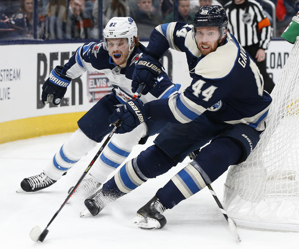 Columbus Blue Jackets' Vladislav Gavrikov, right, of Russia, tries to clear the puck as Winnipeg Jets' Mason Appleton defends during the third period of an NHL hockey game Wednesday, Jan. 22, 2020, in Columbus, Ohio. The Blue Jackets defeated the Jets 4-3. (AP Photo/Jay LaPrete)