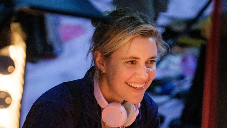 a blond woman in coveralls with pink headphones