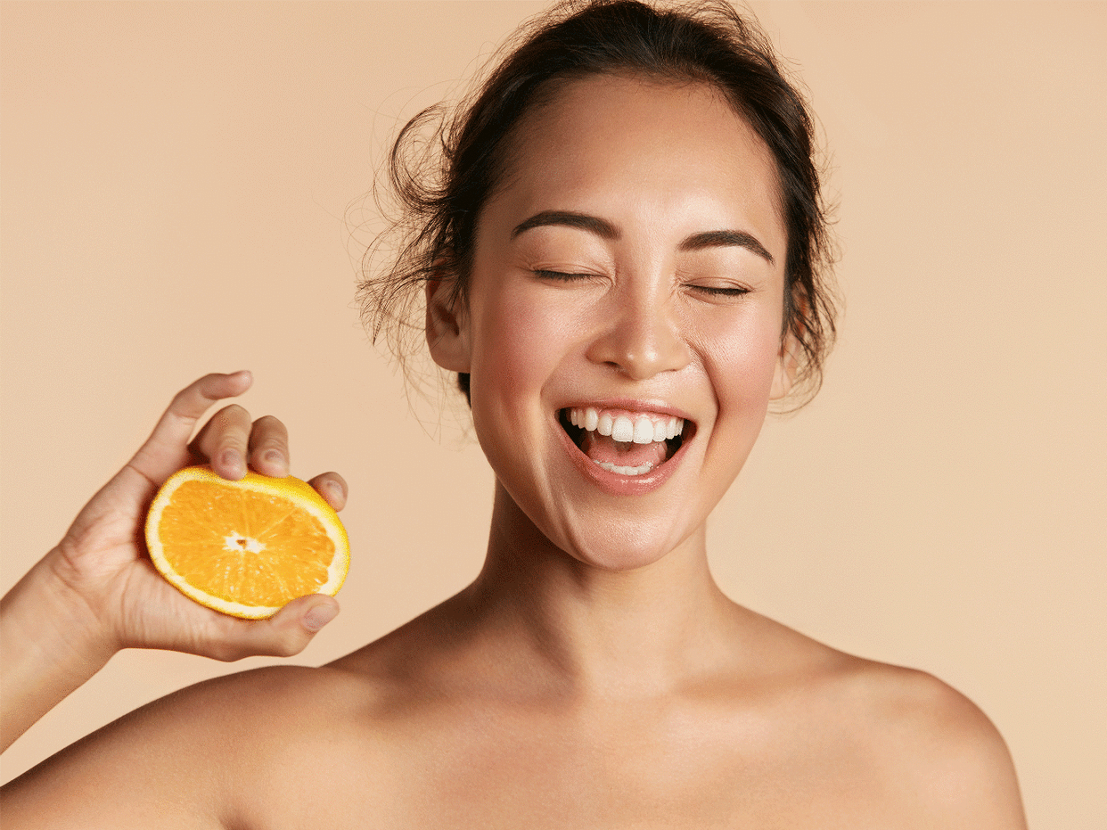 vitamin-c-for-skin: woman squeezing orange