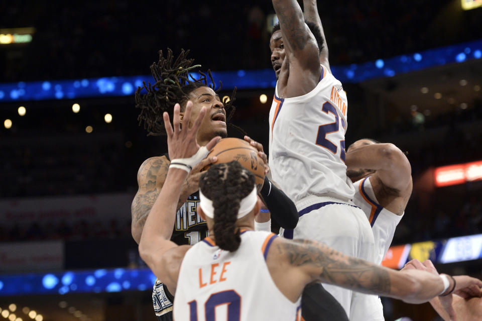 Memphis Grizzlies guard Ja Morant looks to shoot against Phoenix Suns center Deandre Ayton and guard Damion Lee in the second half of an NBA basketball game Tuesday, Dec. 27, 2022, in Memphis, Tenn. (AP Photo/Brandon Dill)