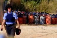 A policewoman walks with dozen of gas bottles in the background in Alcanar, during a search linked to the Barcelona and Cambrils attacks