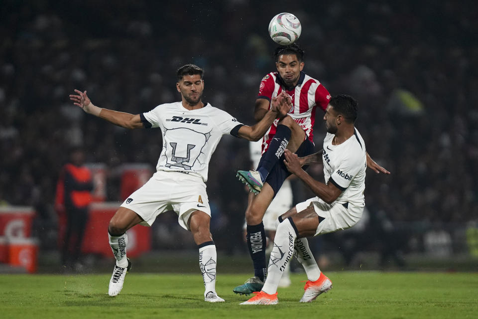 Pumas' Lisandro Magallan, left, and Nathanael Ananias, right, fight for the ball against Chivas' Ricardo Marin, center, during a Mexican soccer league quarterfinal second-leg match in Mexico City, Sunday, Dec. 3, 2023. (AP Photo/Marco Ugarte)