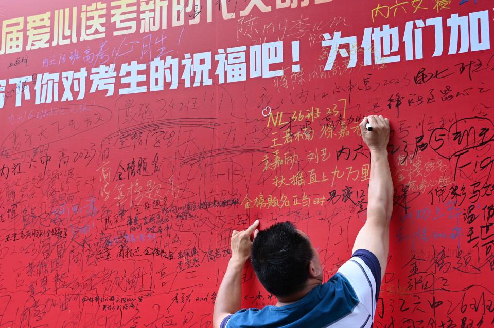 An examinee's father writes his child's name on the wish wall outside an exam venue of the 2023 National College Entrance Exam (aka Gaokao) on June 7, 2023 in Neijiang, Sichuan Province of China. 2023 National College Entrance Exam (aka Gaokao) officially kicks off on June 7. (Photo by