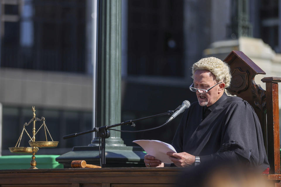 A Freedom and Rights Coalition protester dressed as a judge holds a "mock" trial as they demonstrate outside Parliament in Wellington, New Zealand, Tuesday, Aug. 23, 2022. About 2,000 protesters upset with the government's pandemic response converged on New Zealand's Parliament — but it appeared there would be no repeat of the action six months ago in which protesters camped out on Parliament grounds for more than three weeks. (George Heard/New Zealand Herald via AP)
