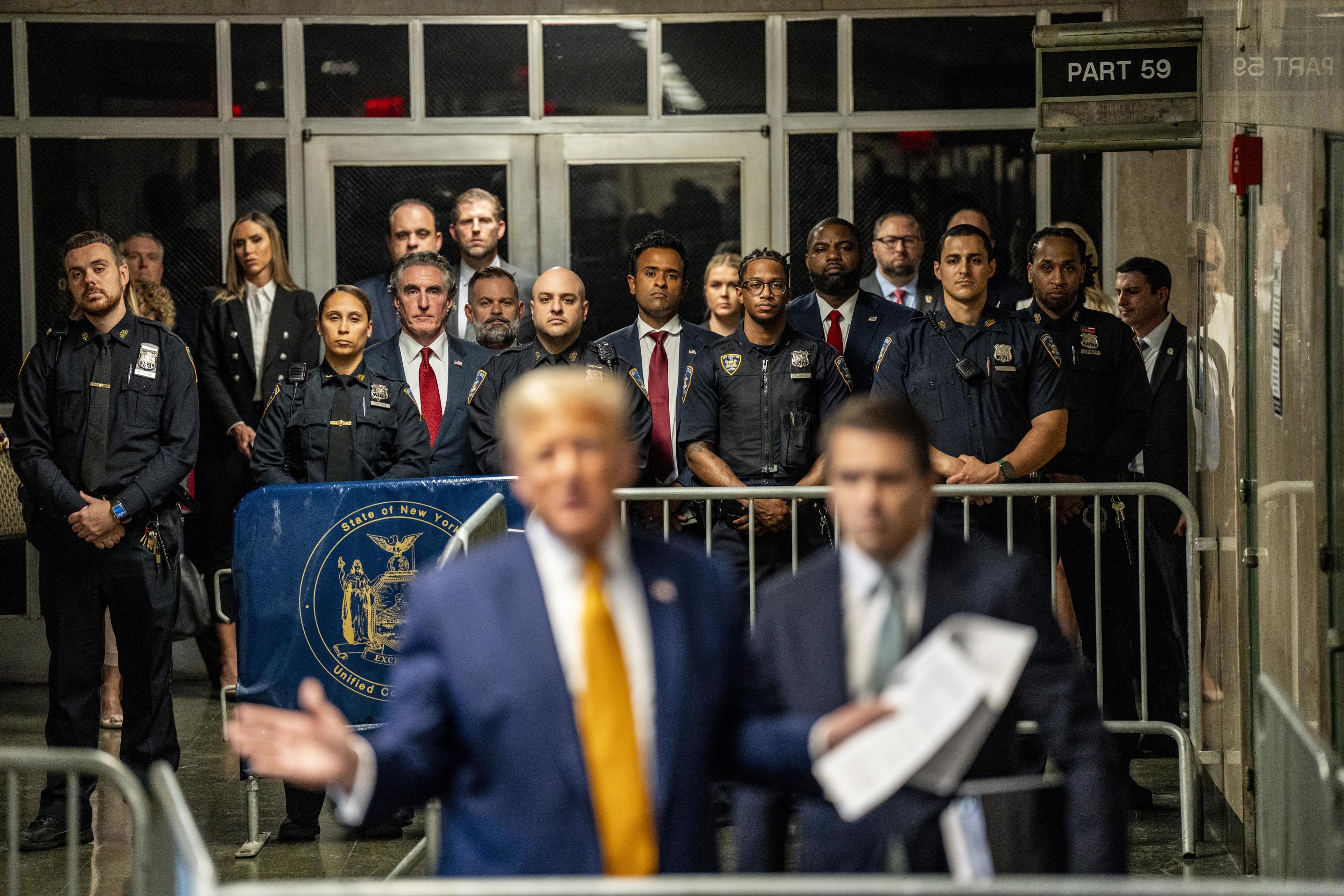 Trump supporters watch as he speaks to reporters inside the Manhattan Criminal Courthouse.