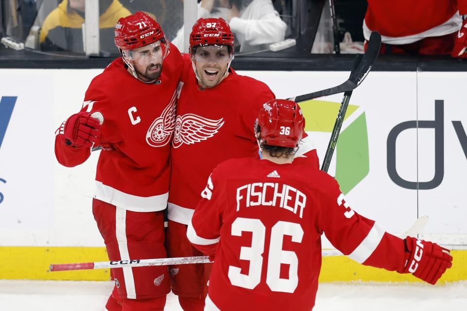 Detroit Red Wings' Dylan Larkin (71) celebrates his open net goal with teammates David Perron (57) and Christian Fischer (36) during the third period of an NHL hockey game against the Boston Bruins, Friday, Nov. 24, 2023, in Boston. (AP Photo/Michael Dwyer)