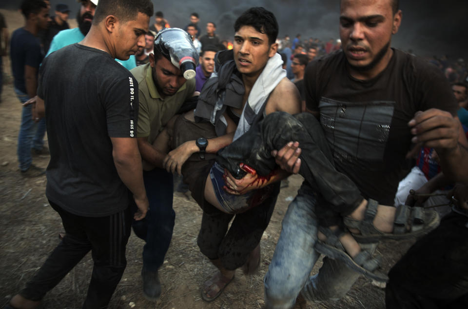 Palestinian protesters evacuate a wounded man shot by Israeli troops during a protest at the Gaza Strip's border with Israel, Friday, Oct. 12, 2018. (AP Photo/Khalil Hamra)