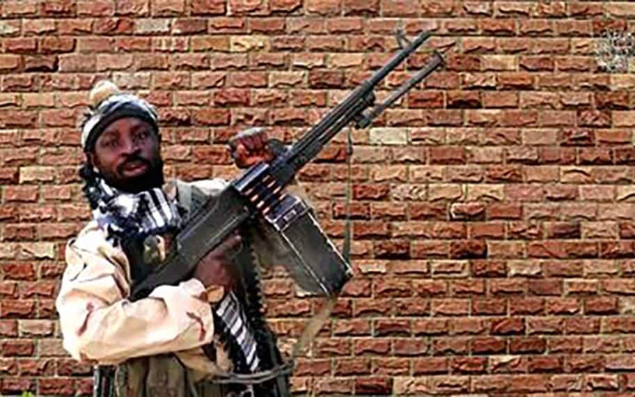 This file screengrab made on January 15, 2018, from a video released the same day by Islamist militant group Boko Haram shows Boko Haram factional leader Abubakar Shekau holding a heavy machine gun at an undisclosed location in Nigeria. - Nigerian Boko Haram leader Abubakar Shekau has been seriously wounded after trying to kill himself to avoid capture during clashes with rival Islamic State-allied jihadists in the north of the country, two intelligence sources said May 20, 2021. Shekau's Boko Haram faction and fighters from the Islamic State West Africa Province had been battling in northeastern Borno state, where ISWAP militants have become the dominant force in Nigeria's more than decade-long jihadist insurgency. Shekau, who made international headlines when his men kidnapped nearly 300 schoolgirls in Chibok in 2014, has been reported dead several times since Boko Haram first began its insurgency in 2009.  - Handout / BOKO HARAM /AFP
