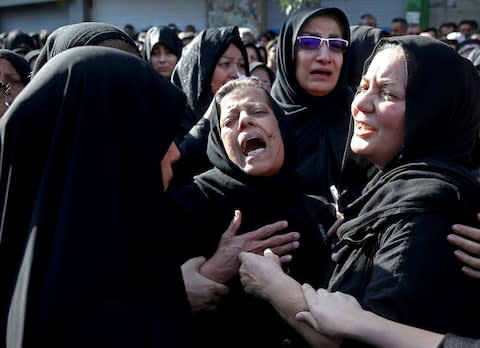 Families of victims of Saturday's terror attack on a military parade in the southwestern city of Ahvaz, that killed 25 people mourn at a mass funeral ceremony - Credit: AP