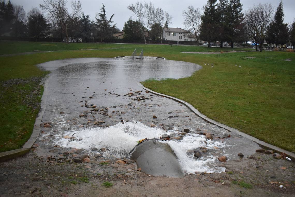 Water pours into the storm basin at Coffee Claratine Neighborhood Park in north Modesto as it rains Monday morning, Jan. 9, 2023.