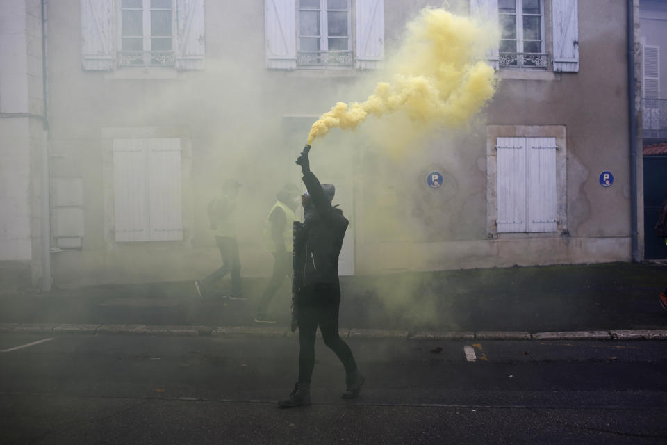 A protestor hold a smoke grande during a demonstration in Bourges, central France, Saturday, Jan. 12, 2019. Paris brought in armored vehicles and the central French city of Bourges shuttered shops to brace for new yellow vest protests. The movement is seeking new arenas and new momentum for its weekly demonstrations. Authorities deployed 80,000 security forces nationwide for a ninth straight weekend of anti-government protests. (AP Photo/Rafael Yaghobzadeh)