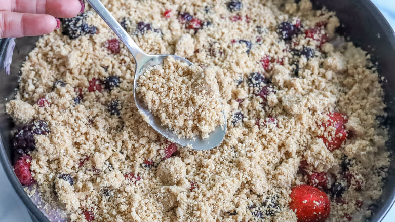 crumble topping being spooned onto cake batter
