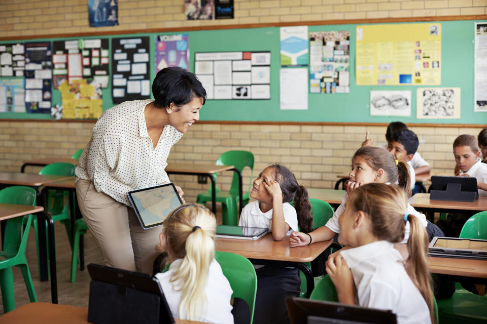 School children in uniforms in class with tablets