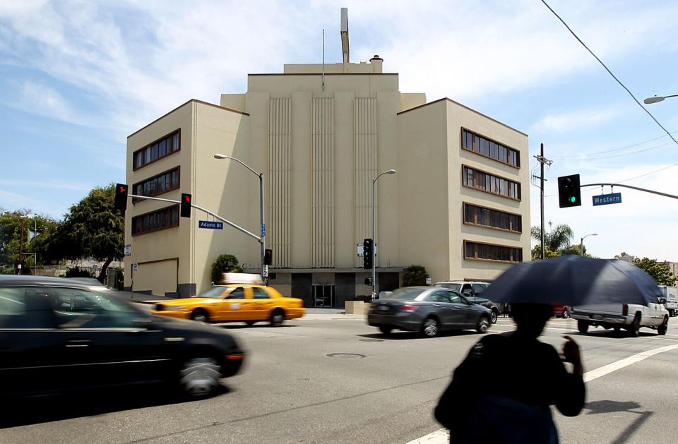 beige office building stands with cards driving past