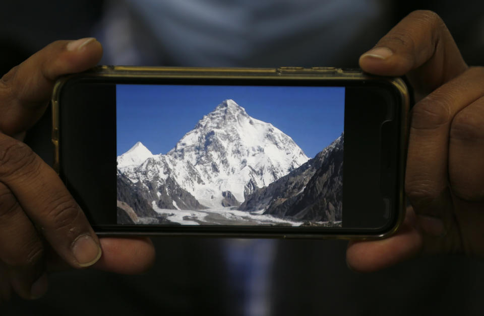 A photo of K2, the world's second-highest mountain, is displayed on a cell phone in Islamabad, Pakistan, Tuesday, Feb. 9, 2021. Families of the three mountaineers who went missing in Pakistan last week while attempting to scale K2 are growing more desperate on Tuesday, a day after bad weather halted the search for the climbers. (AP Photo/Anjum Naveed)