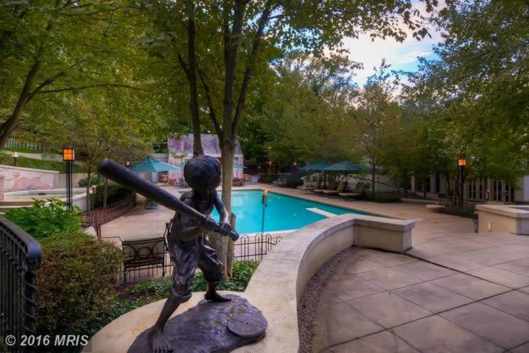 Cal Ripken's pool, with a pool house, torches, deck furniture, and a statue of a boy playing baseball. (Zillow)