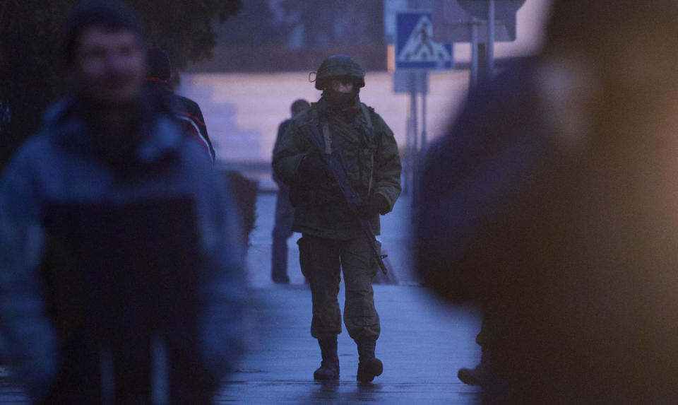 An unidentified armed man patrols a square in front of the airport in Simferopol, Ukraine, Friday, Feb. 28, 2014. Dozens of armed men in military uniforms without markings occupied the airport in the capital of Ukraine's strategic Crimea region. (AP Photo/Ivan Sekretarev)